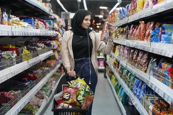 A young Arab woman looks at snacks in a supermarket.