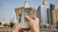 The currency of the United Arab Emirates against the backdrop of Dubai skyscrapers.
