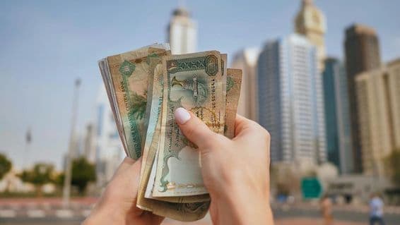 The currency of the United Arab Emirates against the backdrop of Dubai skyscrapers.