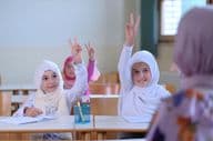 Muslim school students raising their hands to answer teacher's questions.