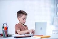 School child talking with teacher via video conference on computer