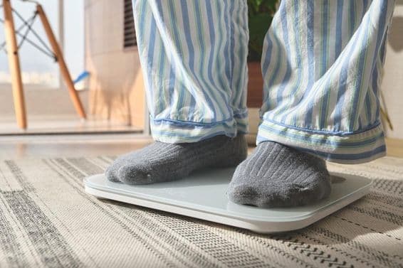 Man in striped pajamas standing on a white digital scale