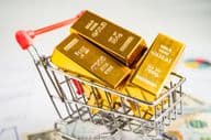 Gold bar in a shopping cart on American dollar bills