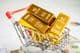 Gold bar in a shopping cart on American dollar bills
