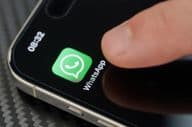 Finger touching the WhatsApp app icon