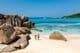 Two travelers walking on the soft white sands of Anse Cocos Beach in Seychelles.