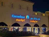 Illuminated logo of Carrefour market with Arabic brand name