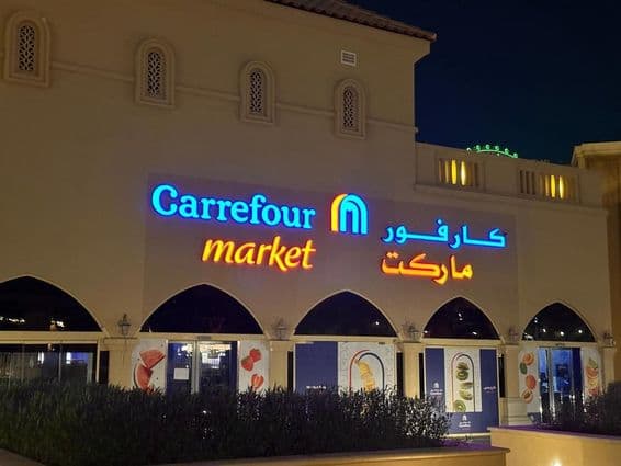 Illuminated logo of Carrefour market with Arabic brand name
