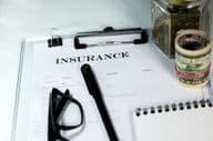 Insurance form with coins and dollar bundle