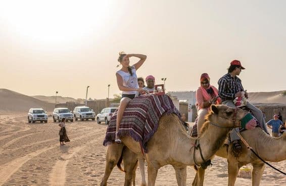 Tourists riding camels in the desert.