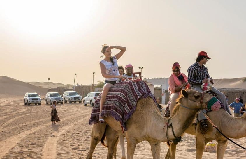 Tourists riding camels in the desert.