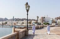 Men in traditional Omani attire along Muscat waterfront.