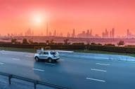 Highway and Dubai cityscape at sunset.