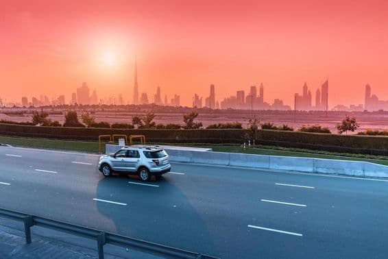 Highway and Dubai cityscape at sunset.