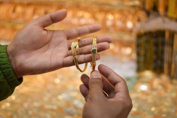 A hand trying on a luxury gold bracelet