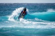 Jetski hits the water above a breaking wave